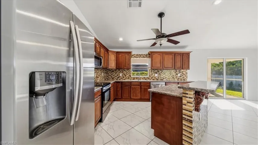 Kitchen with appliances with stainless steel finishes, decorative backsplash, dark stone counters, a kitchen breakfast bar, and recessed lighting