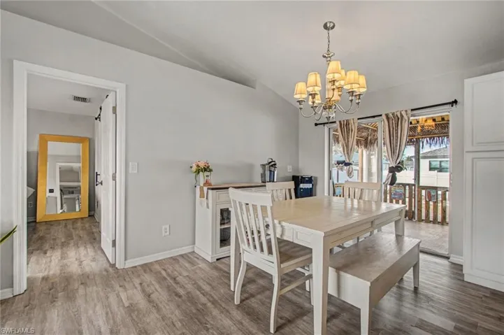 Dining space featuring wood finished floors, vaulted ceiling, and a chandelier