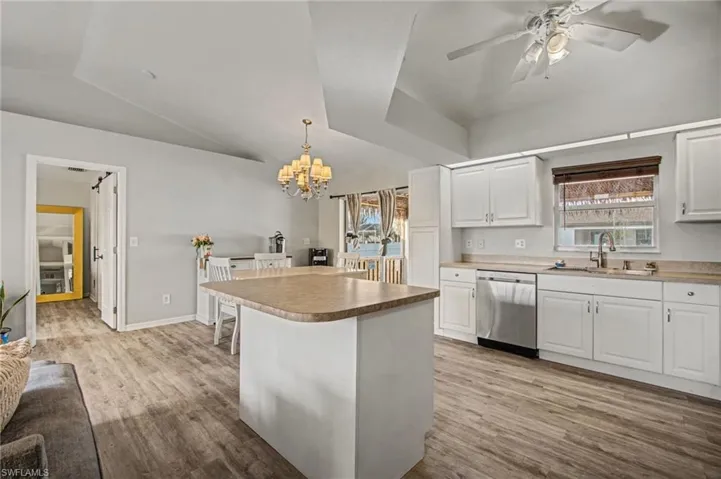 Kitchen featuring white cabinetry, ceiling fan, a center island, stainless steel dishwasher, and light wood finished floors