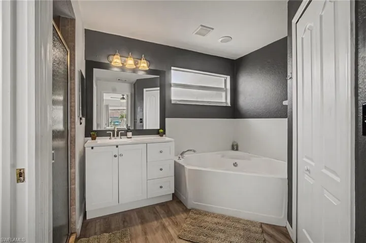 Bathroom featuring vanity, wood finished floors, a garden tub, and a stall shower