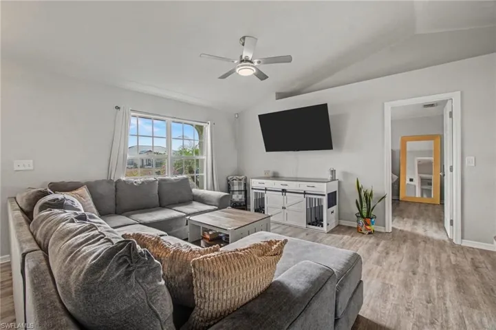 Living room featuring vaulted ceiling, wood finished floors, and ceiling fan