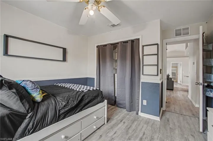Bedroom with light wood-style flooring, ceiling fan, and a closet
