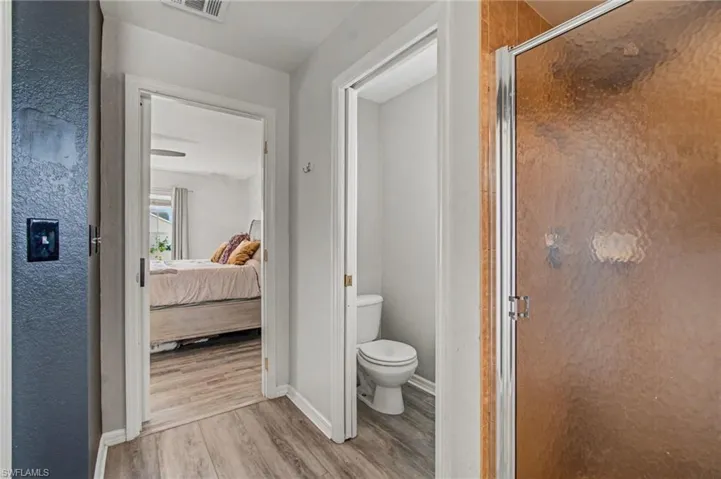 Ensuite bathroom featuring light wood-style flooring and a shower stall