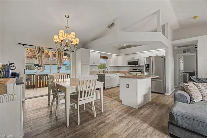 Dining space with vaulted ceiling, light wood-type vinyl flooring