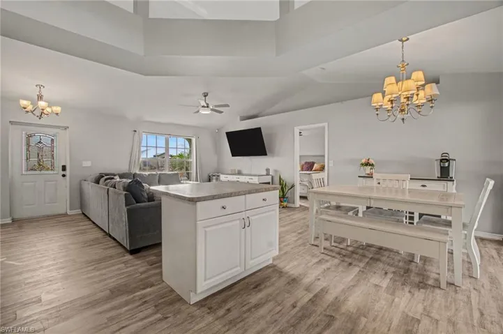 Kitchen featuring  open floor plan, light wood finished floors, a ceiling fan, and white cabinetry