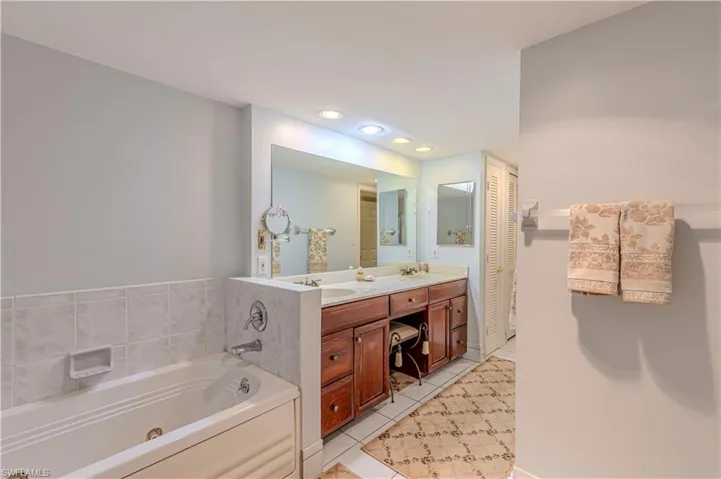 Full bathroom featuring double vanity, recessed lighting, a whirlpool tub, a sink, and tile patterned floors