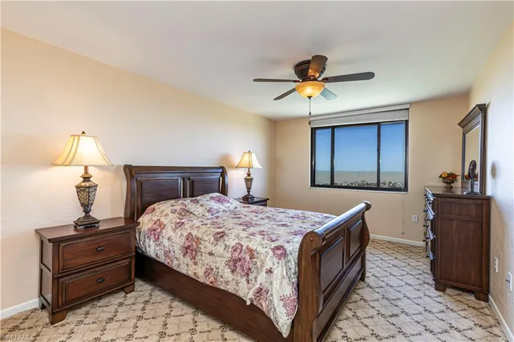 Bedroom with baseboards, light colored carpet, and a ceiling fan