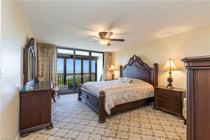 Bedroom featuring access to outside, light carpet, a ceiling fan, and expansive windows