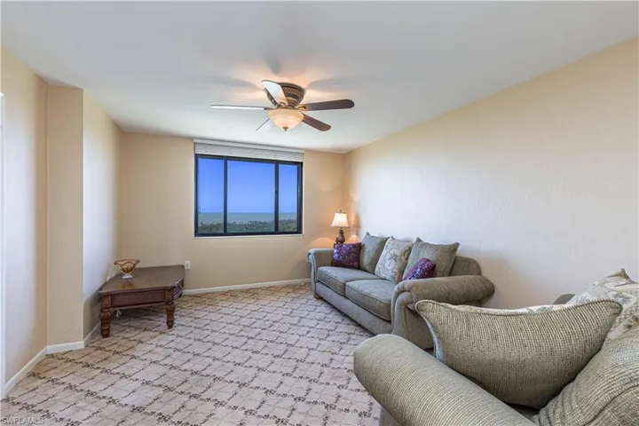 Living room with baseboards, light carpet, and a ceiling fan