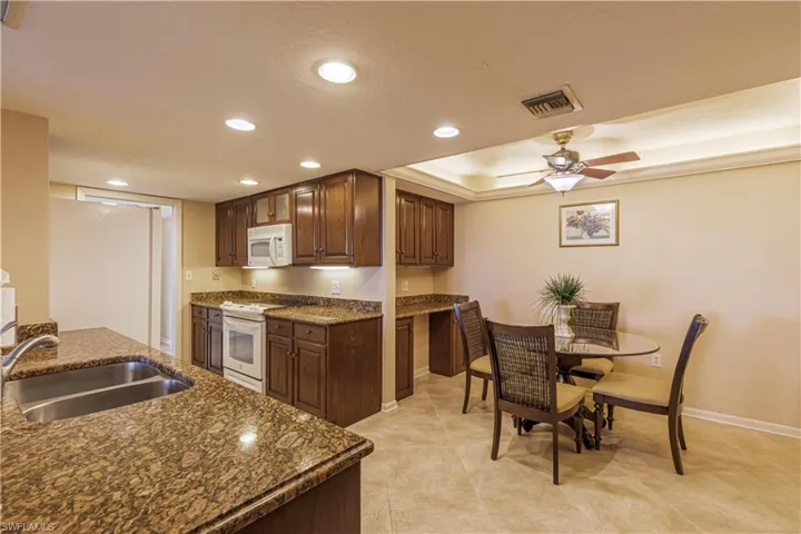 Kitchen featuring visible vents, recessed lighting, white appliances, and a sink