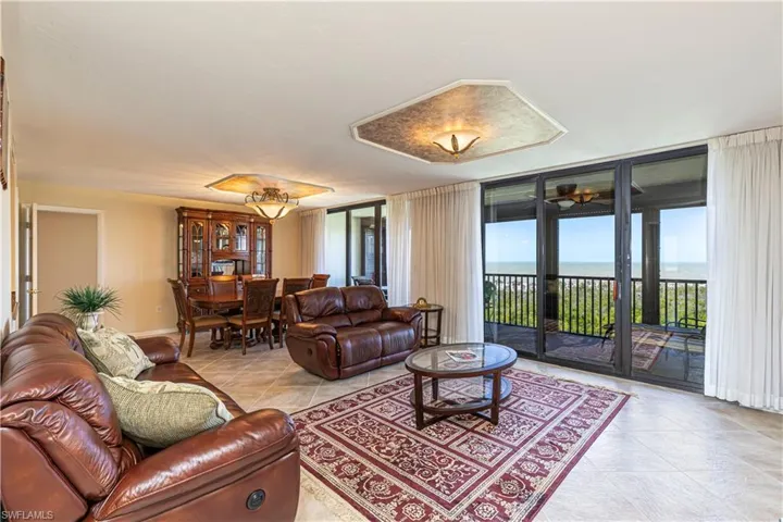 Living area featuring a wall of windows, baseboards, light tile patterned flooring, and a water view