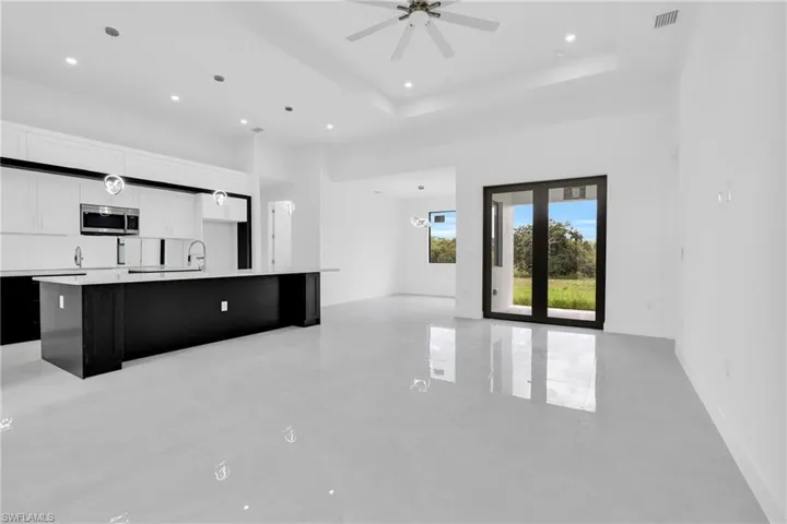 Unfurnished living room featuring recessed lighting, a towering ceiling, ceiling fan, and a tray ceiling