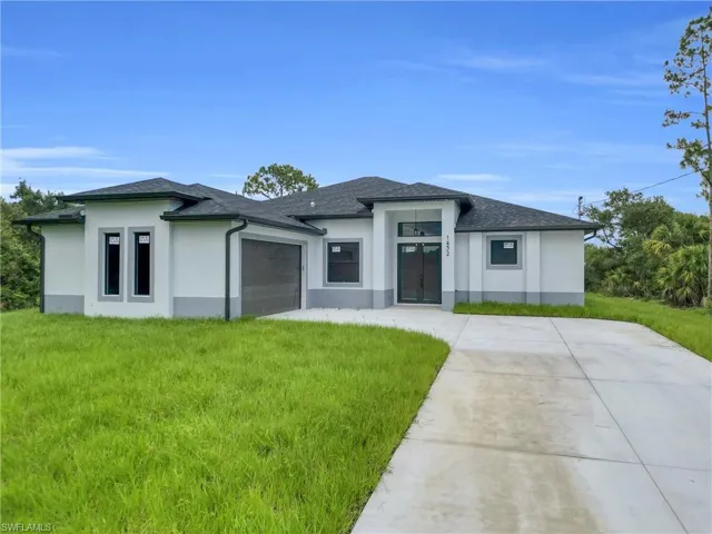 Prairie-style house with stucco siding, an attached garage, and a front lawn