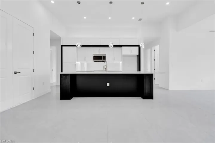 Kitchen with stainless steel microwave, white cabinets, a spacious island, recessed lighting, and light countertops