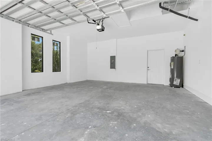 Garage featuring water heater, electric panel, and a garage door opener