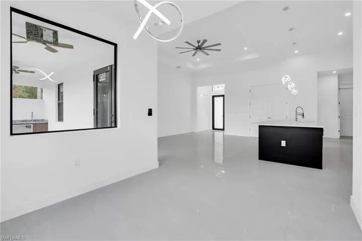 Unfurnished living room featuring recessed lighting, ceiling fan, and a raised ceiling