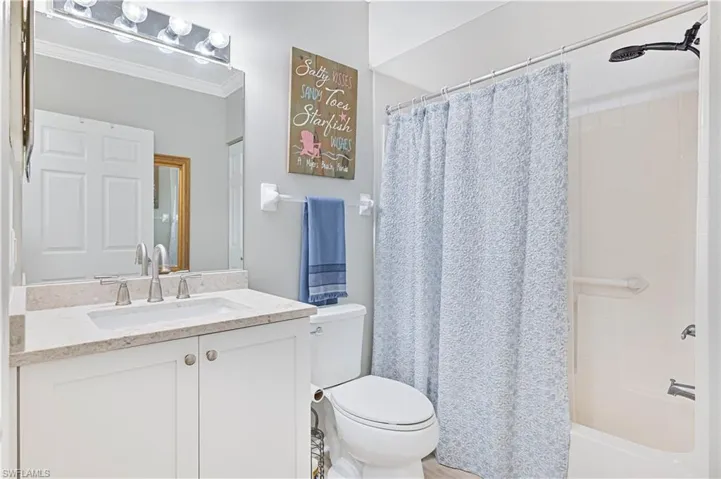 Full guest bathroom with quartz countertop on the vanity, and shower / bathtub combination with curtain.