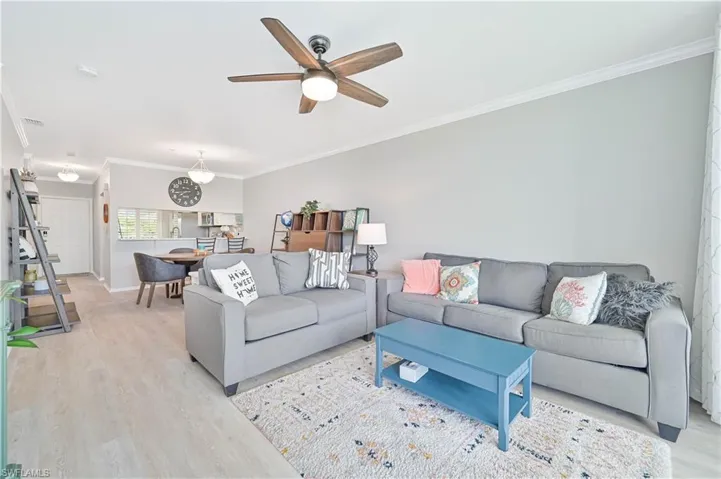 Living room featuring crown molding, light wood-style floors, and ceiling fan
