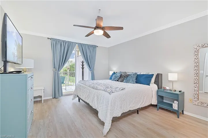Bedroom featuring king bed, ornamental molding, natural light and access to the outside. Vinyl plank flooring and ceiling fan