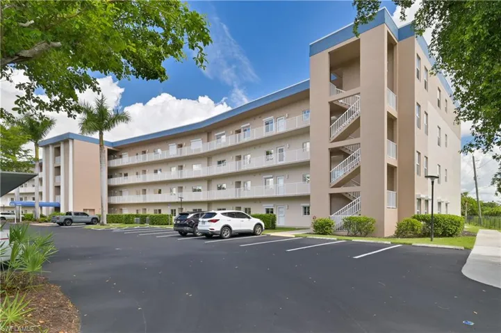 View of apartment building / complex featuring uncovered parking