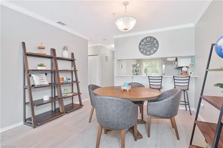 Dining room featuring crown molding, light vinyl plank wood look flooring, and a chandelier