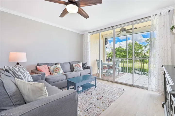 Living room with sleeper sofa, light wood-style floors, crown molding, and lovely water view.