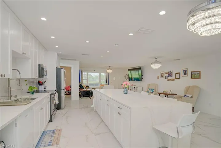 Expansive kitchen island with a light-toned countertop, complemented by white cabinetry and stainless steel appliances