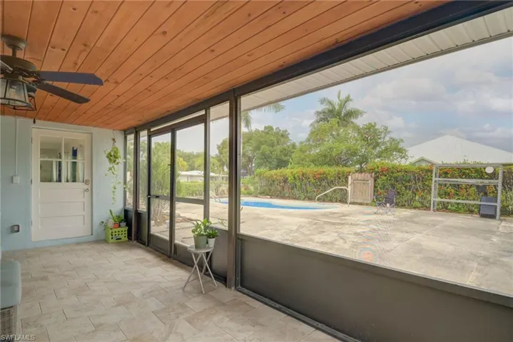 Screened porch featuring a wood-panel ceiling, tiled flooring, and an outdoor ceiling fan