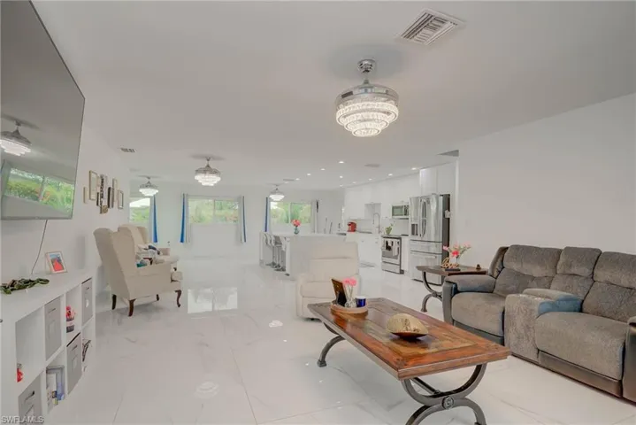 Open-concept living space featuring high-gloss tile flooring, recessed lighting, and multiple crystal-tiered ceiling fixtures