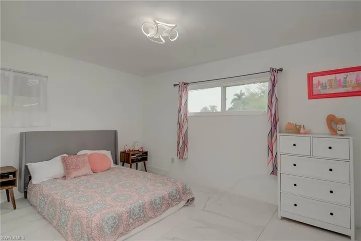 White-tiled flooring and white walls define this bright room, featuring a large window providing natural light
