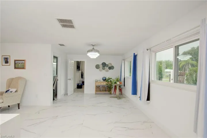 Spacious interior featuring white walls, large windows, and white marble-look flooring