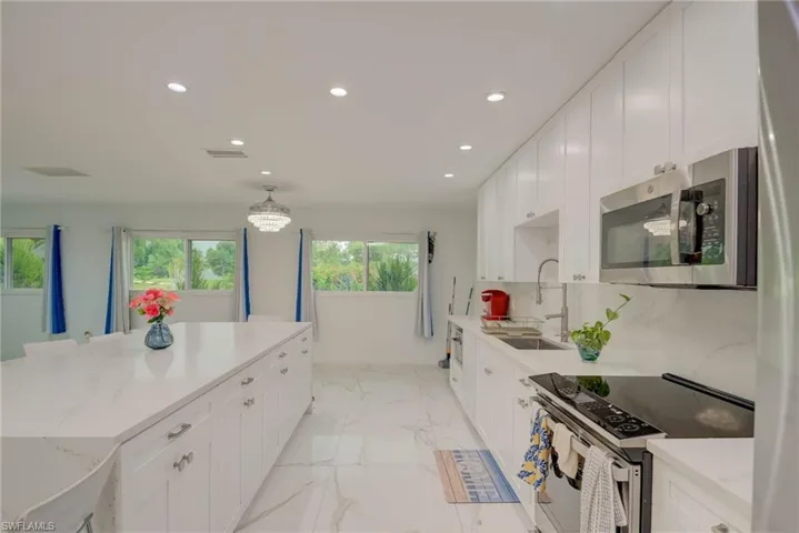 Spacious kitchen featuring white cabinetry, stainless steel appliances, a large center island, recessed lighting, and expansive windows