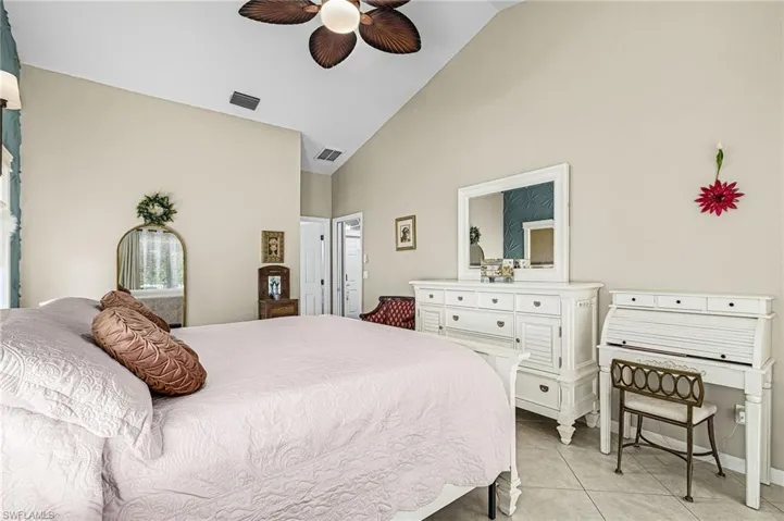 Bedroom with light tile patterned flooring, high vaulted ceiling, and a ceiling fan