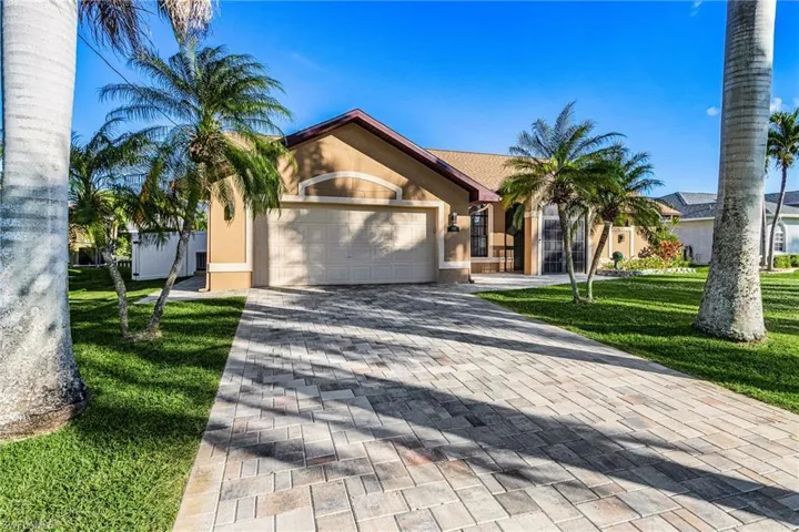 View of front facade featuring stucco siding, a front lawn, decorative driveway, and a garage