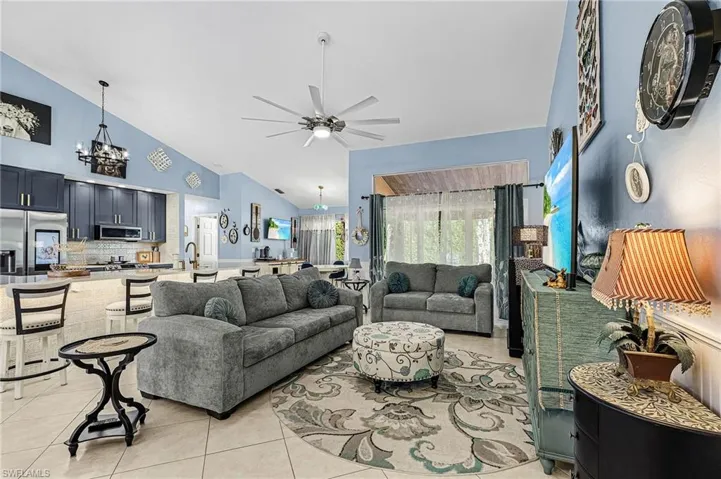 Living room with a chandelier, ceiling fan, light tile patterned floors, and high vaulted ceiling