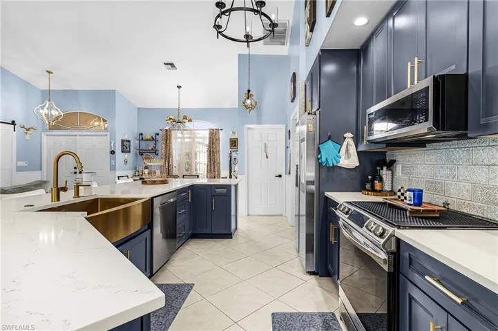 Kitchen featuring stainless steel appliances, blue cabinetry, and a chandelier