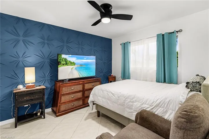 Bedroom with an accent wall, a ceiling fan, and tile patterned flooring