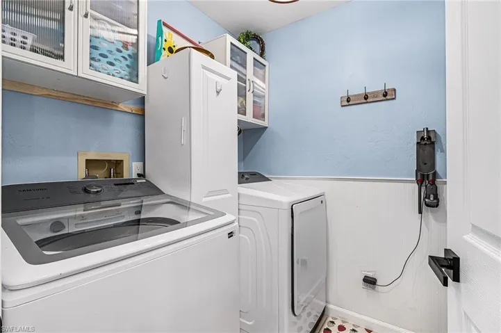 Washroom featuring wainscoting, washing machine and dryer, and cabinet space
