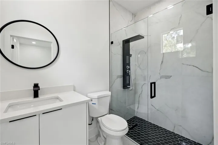 Bathroom with an enclosed shower, toilet, and vanity