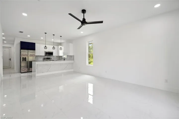 Unfurnished living room with sink and ceiling fan