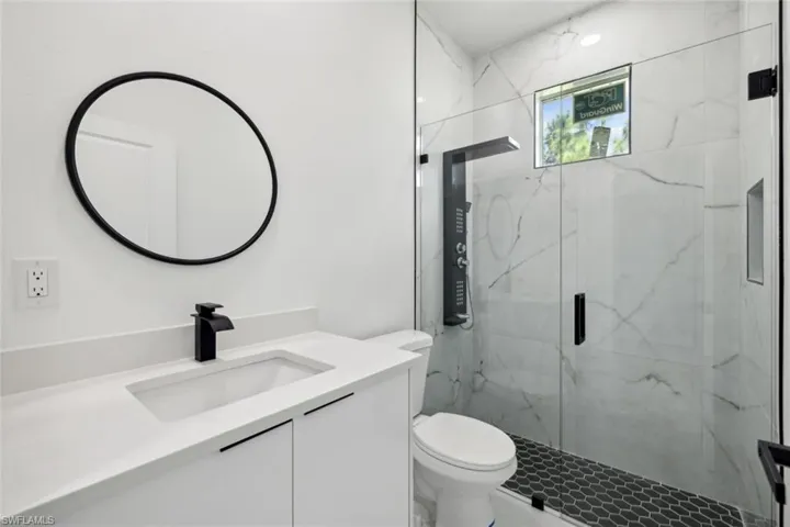 Bathroom with toilet, a shower with door, and vanity