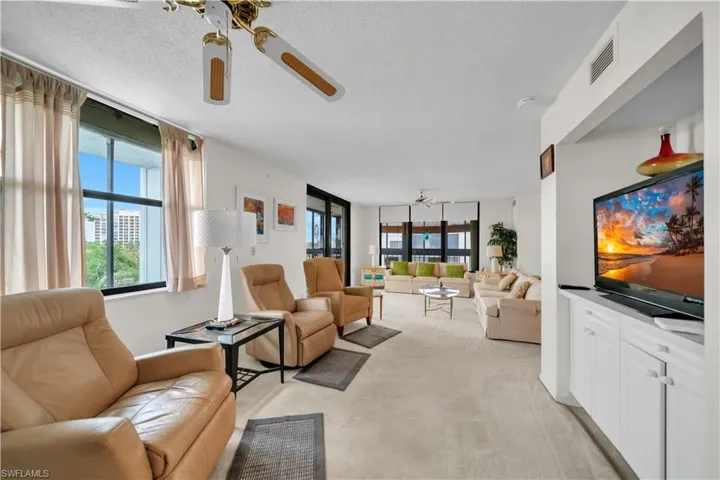 Living room with ceiling fan, a textured ceiling, and light colored carpet
