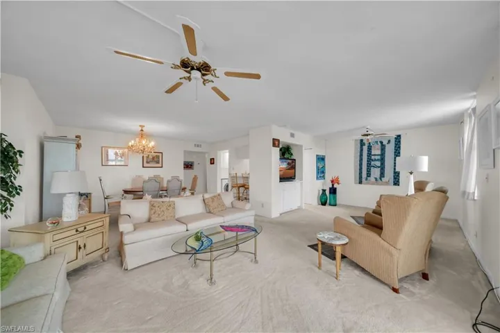 Living area featuring ceiling fan, light colored carpet, and suspended lighting