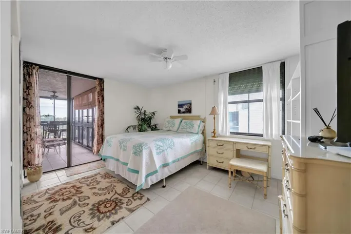 Bedroom featuring access to outside, a textured ceiling, light tile patterned flooring, and ceiling fan