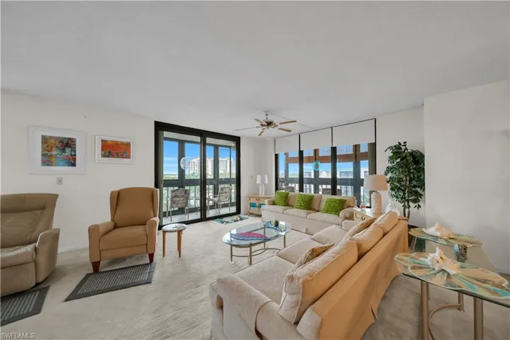 Carpeted living area with healthy amount of natural light, floor to ceiling windows, and ceiling fan