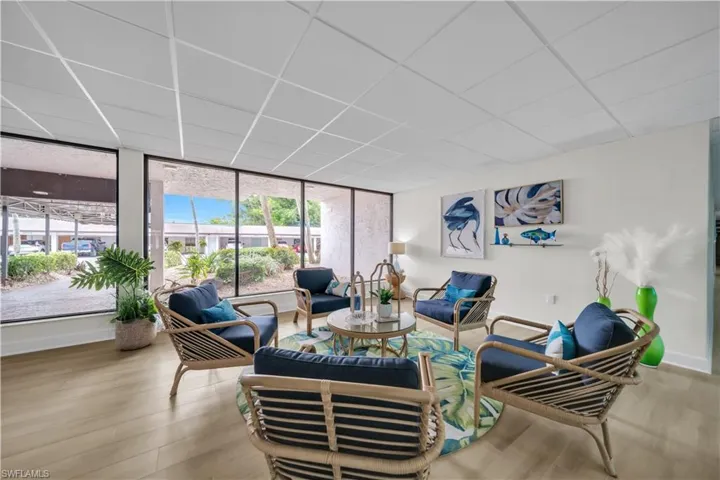 Living room featuring a paneled ceiling, light wood-type flooring, and expansive windows