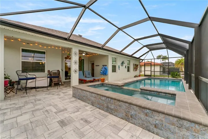 View of swimming pool featuring a sunroom, glass enclosure, a patio, and a pool with connected hot tub