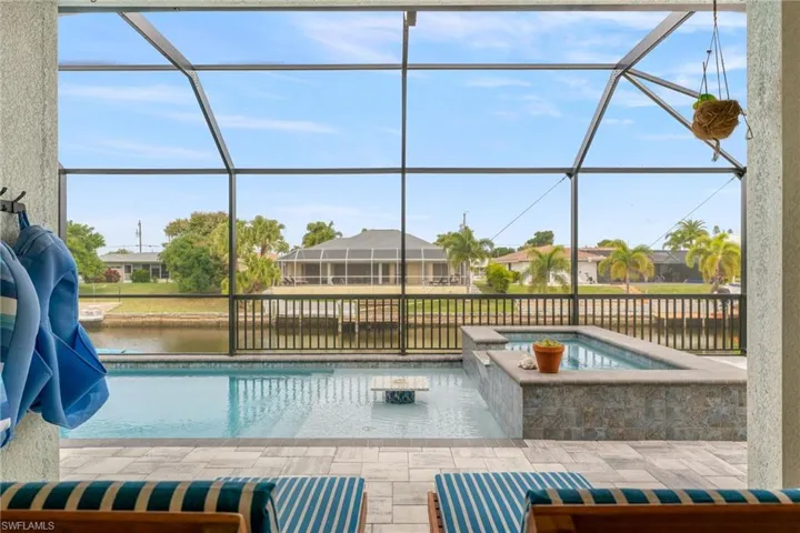 View of pool featuring a sunroom, a lanai, a water view, a patio area, and a residential view