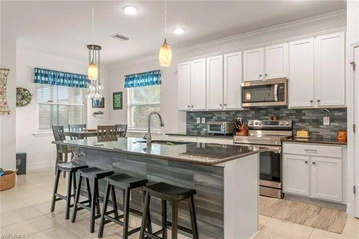 Beautiful Kitchen with White Shaker Style Cabinets, a Large Island with Granite Countertops & Stainless Steel Appliances