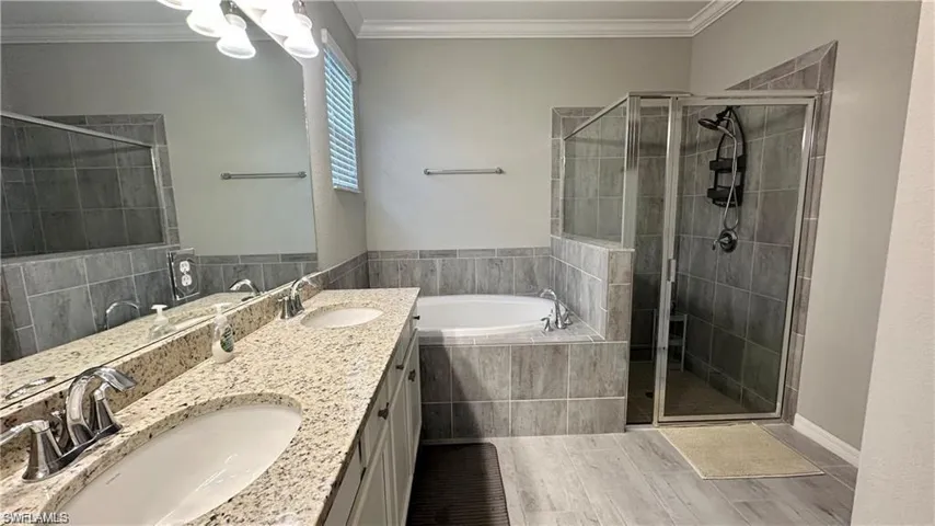 Bathroom featuring a sink, a bath, and crown molding